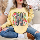Leopard Floral Easter Occupation DTF Heat Transfer, colorful floral and leopard print design with the words 'School Nurse' on a yellow sweatshirt worn by a woman.