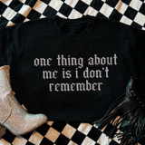 One Thing About Me Is I Don’t Remember LIGHT GREY DTF Heat Transfer, decorative black t-shirt with white gothic text on a checkered background, with silver and black fringe boots.