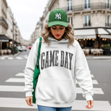 Distressed Game Day BLACK DTF Heat Transfer, a black heat transfer design shown on a white hoodie worn by a woman in an urban street setting.