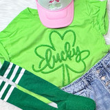 Lucky Fluffy Chenille Shamrock Patch, bright green shamrock patch with fluffy texture and the word 'Lucky' embroidered inside, on a neon green t-shirt.