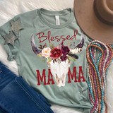 Blessed Mama Skull with Flowers Screen Print Heat Transfer, design featuring a cow skull with floral and feather accents on a mint green T-shirt, surrounded by accessories like star earrings, a hat, and colorful bead necklaces.