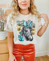 Howdy Easter Horse DTF Heat Transfer, colorful and detailed heat transfer design of a horse with Easter-themed accessories, including bunny ears, flowers, and playing cards on a woman's t-shirt.
