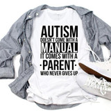 Autism Doesn't Come With A Manual Sublimation Transfer T-Shirt, white shirt with black text and design about autism and parents, laid on a gray shirt with white sneakers and a brown shoelace visible.