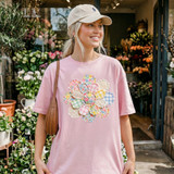 Faux Fabric Patchwork Flower DTF Heat Transfer, close-up of colorful patchwork flower design on a pink T-shirt worn by a woman at a flower shop