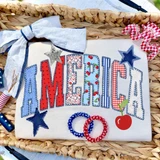 Faux Stitching Patchwork America DTF Heat Transfer, embroidered fabric with patriotic design featuring the name 'America' in stitched patchwork style, stars, cherry print, and decorative elements for clothing or accessories.
