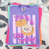 You're A Glitter Dumpling Stripes DTF Heat Transfer, colorful design with a smiling holographic glitter dumpling inside a bamboo steamer on a purple t-shirt.
