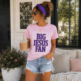 BIG JESUS FAN Purple Puff Screen Print Transfer, woman wearing a pink t-shirt with purple puff print text 'BIG JESUS FAN' and holding iced coffee in a casual outdoor setting.