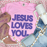 Jesus Loves You Purple PUFF Transfer, product display with pink T-shirt, cowboy boots, mug, beaded necklace, and jeans on a heart-patterned background.