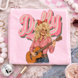 Retro Vintage Dolly DTF Heat Transfer, pink t-shirt with vintage style illustration of a woman playing guitar and the word 'Dolly' in retro font.
