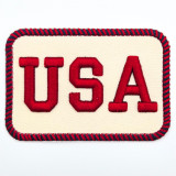 Retro USA Puff Embroidered Patch – 4” Wide, close-up of a rectangular fabric patch with red embroidered letters 'USA' on a cream background and a red and navy striped border.