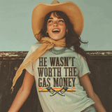 He Wasn't Worth The Gas Money DTF Heat Transfer, a cheerful woman wearing a large sunhat and a neckline scarf, smiling outdoors with a graphic T-shirt featuring this phrase and decorative elements.