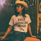 Women Supporting Women DTF Heat Transfer, a woman wearing a white T-shirt with the text 'Women Supporting Women Since Forever' printed on it, paired with a cowboy hat in a vintage-themed setting.
