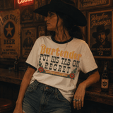 Product Bartender Put His Tab On Regret DTF Heat Transfer, woman wearing a T-shirt with the phrase "Bartender Put His Tab On Regret" and decorative floral graphics, in a rustic bar setting.