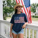 Seashell Flag DTF Heat Transfer, patriotic girl wearing navy T-shirt with seashell flag design, American flag in background, on a porch.