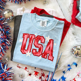 Faux Painted USA DTF Heat Transfer, patriotic T-shirt with USA design surrounded by patriotic decorations.