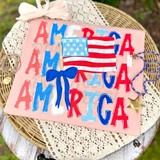 Stacked America With Flag DTF Heat Transfer, patriotic American flag-themed design featuring colorful letters, a flag illustration, and decorative elements on a pink background.