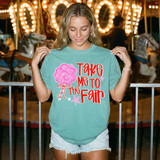 Take Me To The Fair DTF Heat Transfer, a vibrant pink cotton candy graphic with star accents on a teal t-shirt worn by a smiling young woman at a fairground.