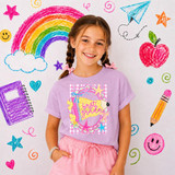 Preppy Grade Pennant DTF Heat Transfer, colorful design featuring first grade message with stars, ribbons, and playful elements on a girl's t-shirt in front of a creative background.
