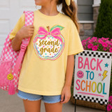 Polka Dot Grade Apple DTF Heat Transfer, colorful polka dot design with the words 'second grade' and a pink bow, on a girl's yellow T-shirt.