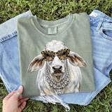 Glam Cow DTF Heat Transfer, a graphic of a fashionable cow wearing sunglasses and jewelry, printed on a green T-shirt.