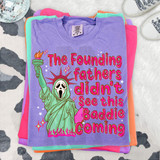 The Founding Fathers Didn't See This Baddie Coming, DTF Heat Transfer, vibrant purple T-shirt with a colorful graphic of the Statue of Liberty wearing a ghost mask, surrounded by stars and flames.