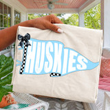 Pennant Teams DTF Heat Transfer, a blue and white flag-shaped design with the word 'Huskies' and black-and-white checkered accents, attached to a blanket with a black bow.
