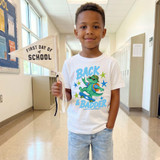 Back And Badder Retro Gator DTF Heat Transfer, a colorful graphic T-shirt featuring a cool cartoon gator skateboarding with sunglasses and a backpack, designed for children's back-to-school wear.