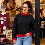 Blank Mockneck Sweatshirt — Preorder | Multiple Colors, woman wearing black mock neck sweatshirt with red cuffs and collar, paired with light blue jeans, standing outside a clothing store.