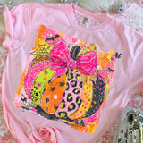 Colorful Coquette Pumpkin DTF Heat Transfer, vibrant pink Halloween pumpkin design with a large bow, leopard print, and spooky elements on a pink t-shirt.