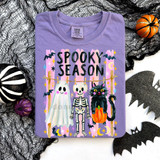 Spooky Season Halloween Friends DTF Heat Transfer, purple t-shirt with spooky Halloween graphic of a ghost, skeleton, and black cat with pumpkin, surrounded by bats, moons, and stars.