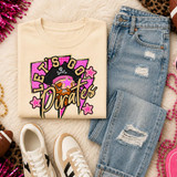 Pink Glitter Mascot - 62 teams - DTF Heat Transfer, a colorful graphic t-shirt featuring a pirate mascot with pink glitter details and playful text, laid out on casual denim jeans and white sneakers surrounded by party accessories.