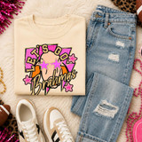 Pink Glitter Mascot - 62 Teams - DTF Heat Transfer, a colorful t-shirt with a fun graphic design featuring a mascot and pink glitter stars, laid out with distressed jeans, sneakers, and accessories on a fluffy surface.