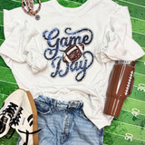 Game Day Sequin Patch With Football, casual sports-themed outfit with a white sweatshirt featuring a football and the words 'Game Day' in sequins, paired with blue jeans, white sneakers, a brown tumbler, and a pink wristband, laid out on a green football field background.