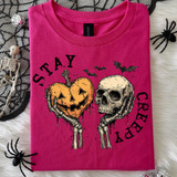 Stay Creepy Halloween BLACK DTF Heat Transfer, graphic t-shirt with spooky skeleton holding a pumpkin and a skull, Halloween themed design.