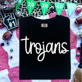 Trojans WHITE DTF Heat Transfer, a black T-shirt featuring the word 'trojans' in white script, surrounded by sports-themed decorations and party accessories.
