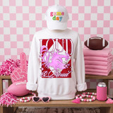 Loud & Proud Mascot DTF Transfers | Retro School Spirit Mascot Collection, pink-themed display with a white sweatshirt featuring a pink dragon mascot design, a white cap with colorful embroidery, and various school spirit accessories on a wooden table.