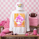 Loud & Proud Mascot DTF Transfers | Retro School Spirit Mascot Collection, vibrant and colorful mascot design on a white sweatshirt, surrounded by pink sports-themed accessories in a playful setting.
