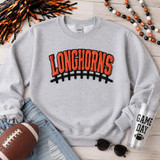 Longhorns Orange Chenille Football Apparel Patch, close-up of a gray sweatshirt with orange and black chenille patch embroidered 'Longhorns' over a football-lace design. Includes football, jeans, sunglasses, and a tumbler with 'Game Day' text for a sports fan themed setup.