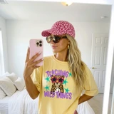 Teaching Wild Things DTF transfer with purple lettering, leopard cub wearing star sunglasses, and teal star accents on a yellow shirt