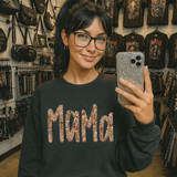 Leopard Mama DTF Transfer | Animal Print Mom DTF, woman wearing a black sweatshirt with leopard print text design, shopping in a store with animal print accessories and clothing in the background.
