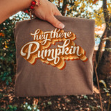 Hey There Pumpkin DTF Transfer, retro fall script design on a folded brown fabric.