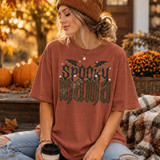 Spooky Mama DTF transfer with gothic lettering, leopard print fill, bat wings, and stars on a rust colored t-shirt