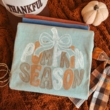 Pumpkin Season DTF transfer with retro groovy lettering in orange, brown, and white, topped with a white bow, on a sage green shirt