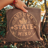 Autumn State of Mind DTF transfer with distressed circular stamp design, maple leaf graphic, and burnt orange lettering on a brown shirt