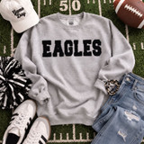 Black EAGLES fluffy appliqué patch with bold varsity lettering and soft plush texture on gray sweatshirt