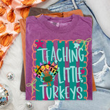 Teaching Little Turkeys DTF transfer with turkey made of crayon feathers holding a chalkboard on a teal striped background