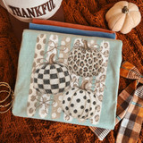 Fall pumpkin trio DTF transfer with checkered, leopard print, and polka dot pumpkin designs on a striped background with stitched bow accents