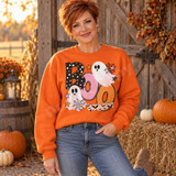 Boo Halloween DTF transfer with polka-dot bubble lettering, two cute ghosts, spiderwebs, stars, and a bat-print washi strip accent Shown on a Orange crewneck sweatshirt.