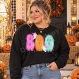 Pastel BOO Halloween DTF transfer with pink, orange, and mint scalloped lettering and two cute ghosts wearing pink bows Shown on a Black crewneck sweatshirt.