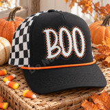 BOO Halloween DTF transfer in chunky white block letters with black-and-orange polka-dot trim and hand-drawn motion lines on a dark sweatshirt Shown on a black foam front panel with an orange rope and black-and-white checkered mesh back trucker hat.